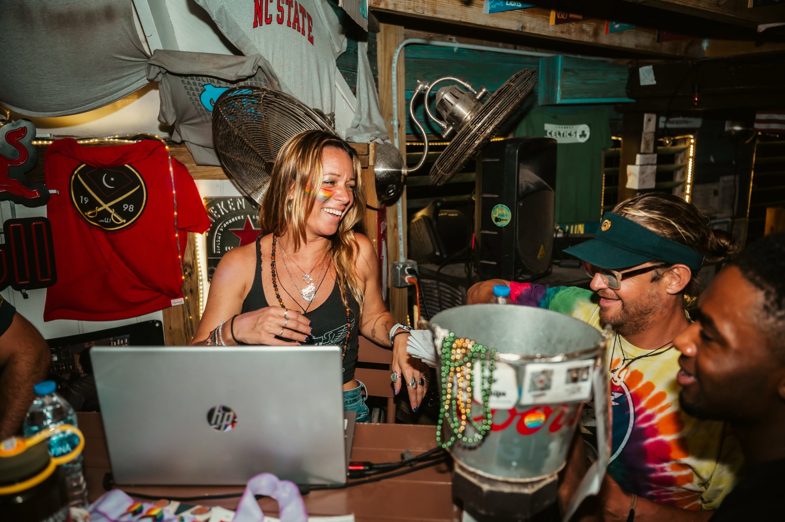 Angela at her DJ booth with rainbow face paint, laughing